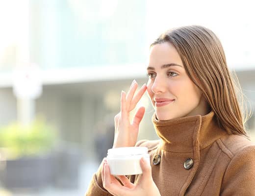 Beautiful Young Lady applying skin cream in the winter