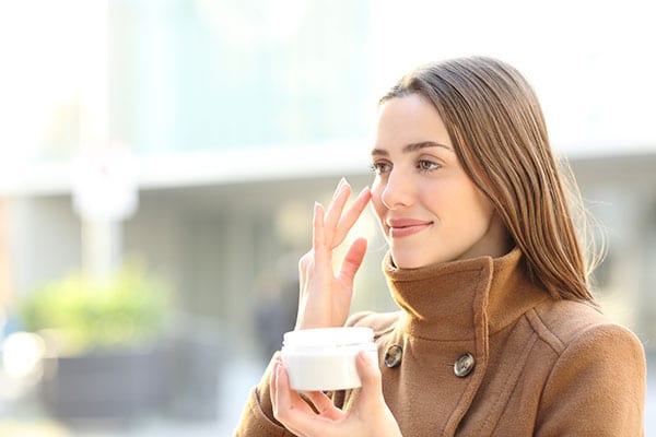 Beautiful Young Lady applying skin cream in the winter